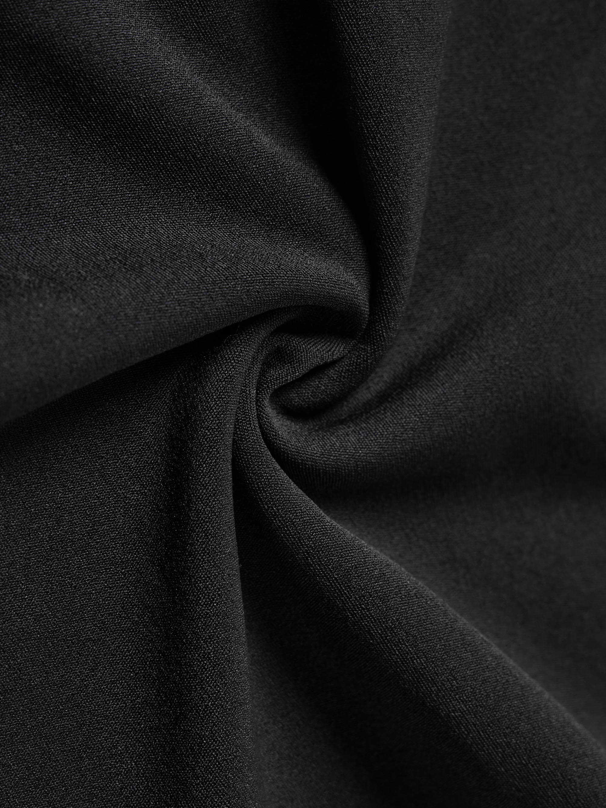 Close-up of black fabric, twisted to show the softness.