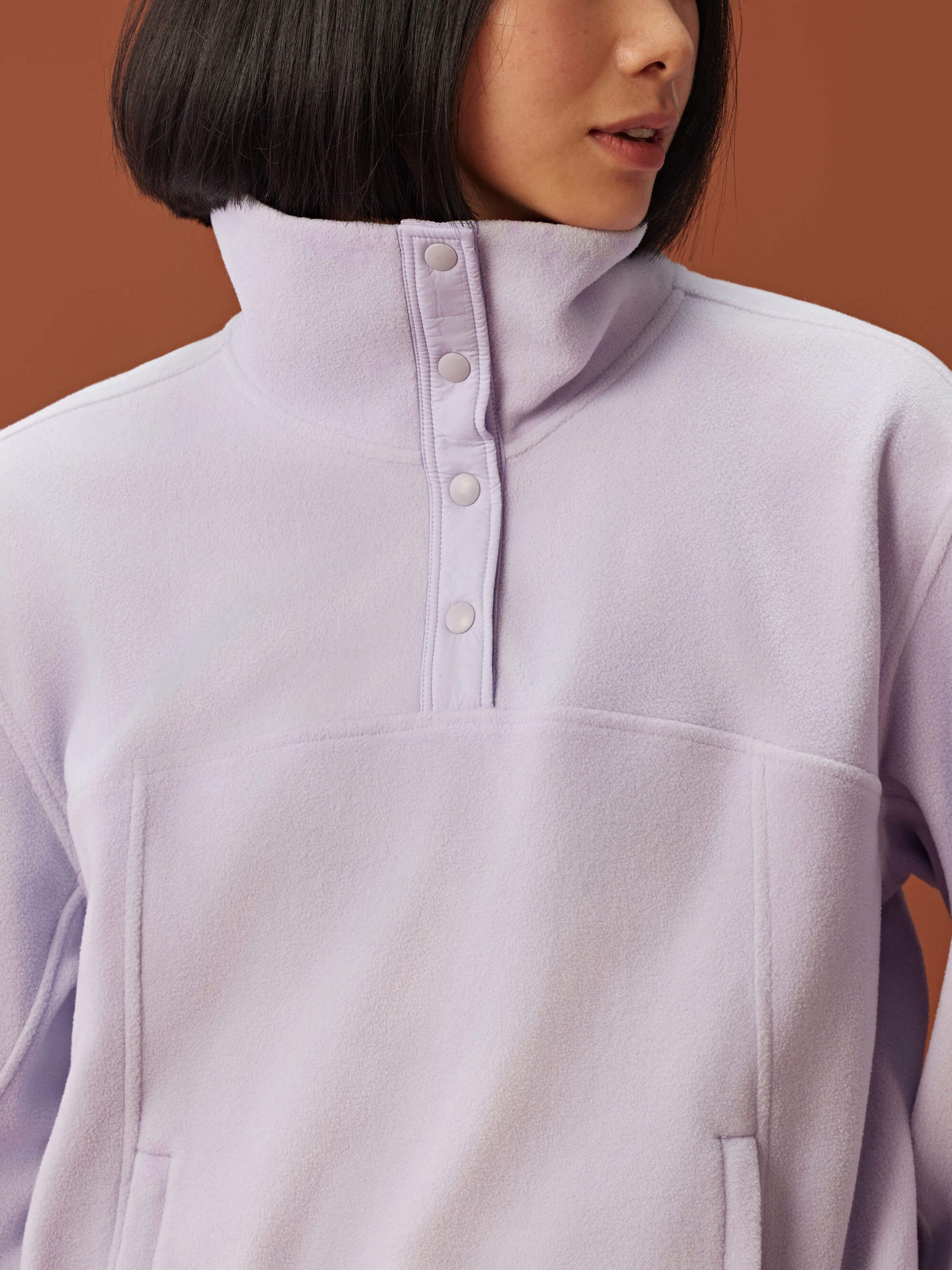 close up of woman in light purple fleece sweatshirt showcasing the buttons on collar