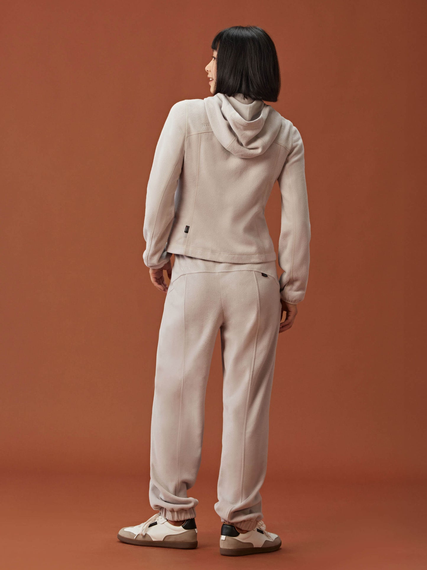 back of woman in beige hoodie and pants