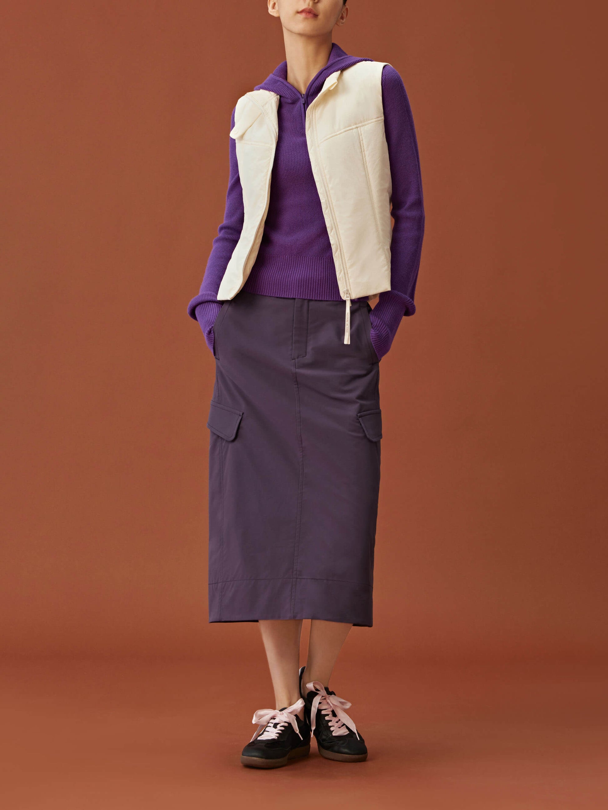 woman in purple hoodie, white vest and dark purple midi skirt.