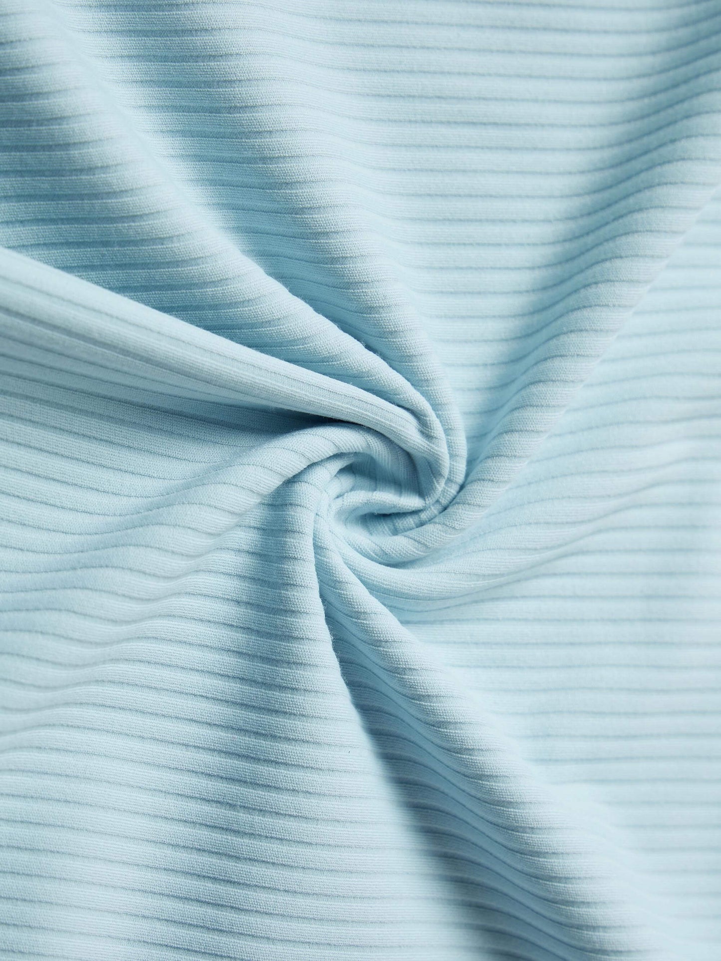 Close-up of light blue ribbed fabric, twisted into a spiral pattern.