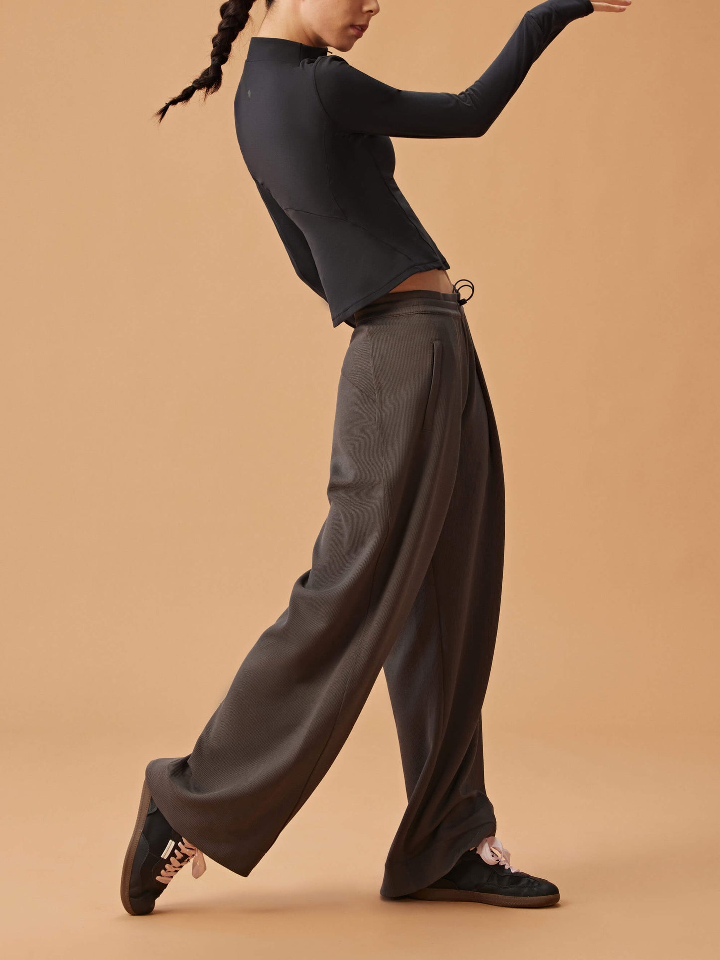 Side view of woman wearing black half zip long sleeve top and dark gray sweatpants