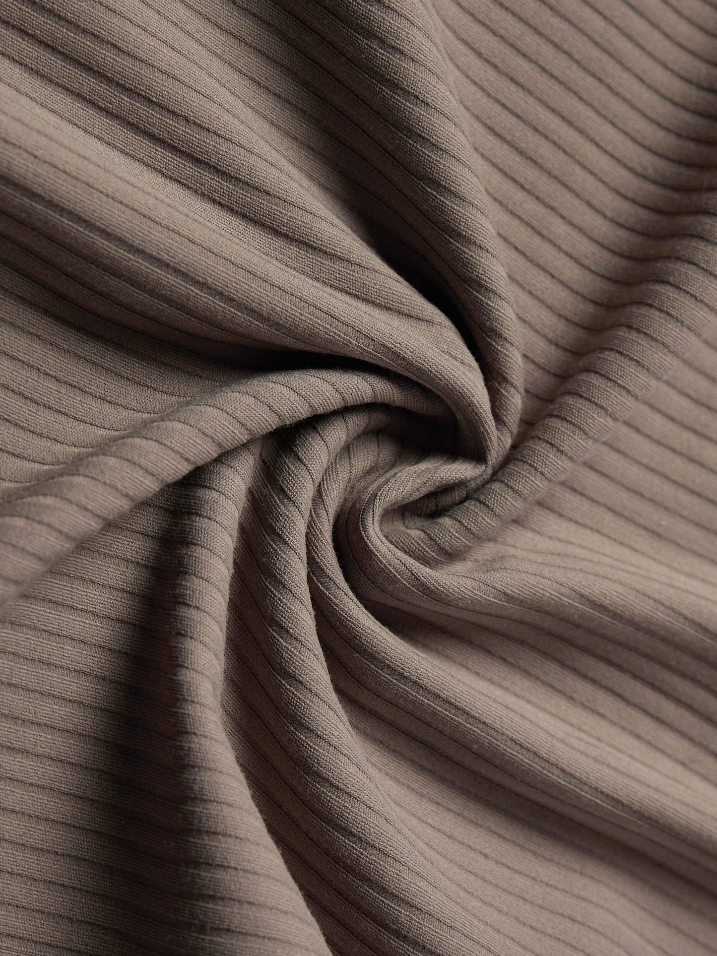 Close-up of beige ribbed fabric, showing its texture and soft folds.