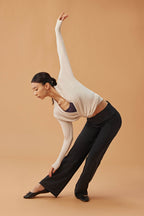 woman dancing in white cardigan, dark purple sports bra and black wide leg pants