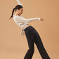 woman dancing in white cardigan, dark purple sports bra and black wide leg pants