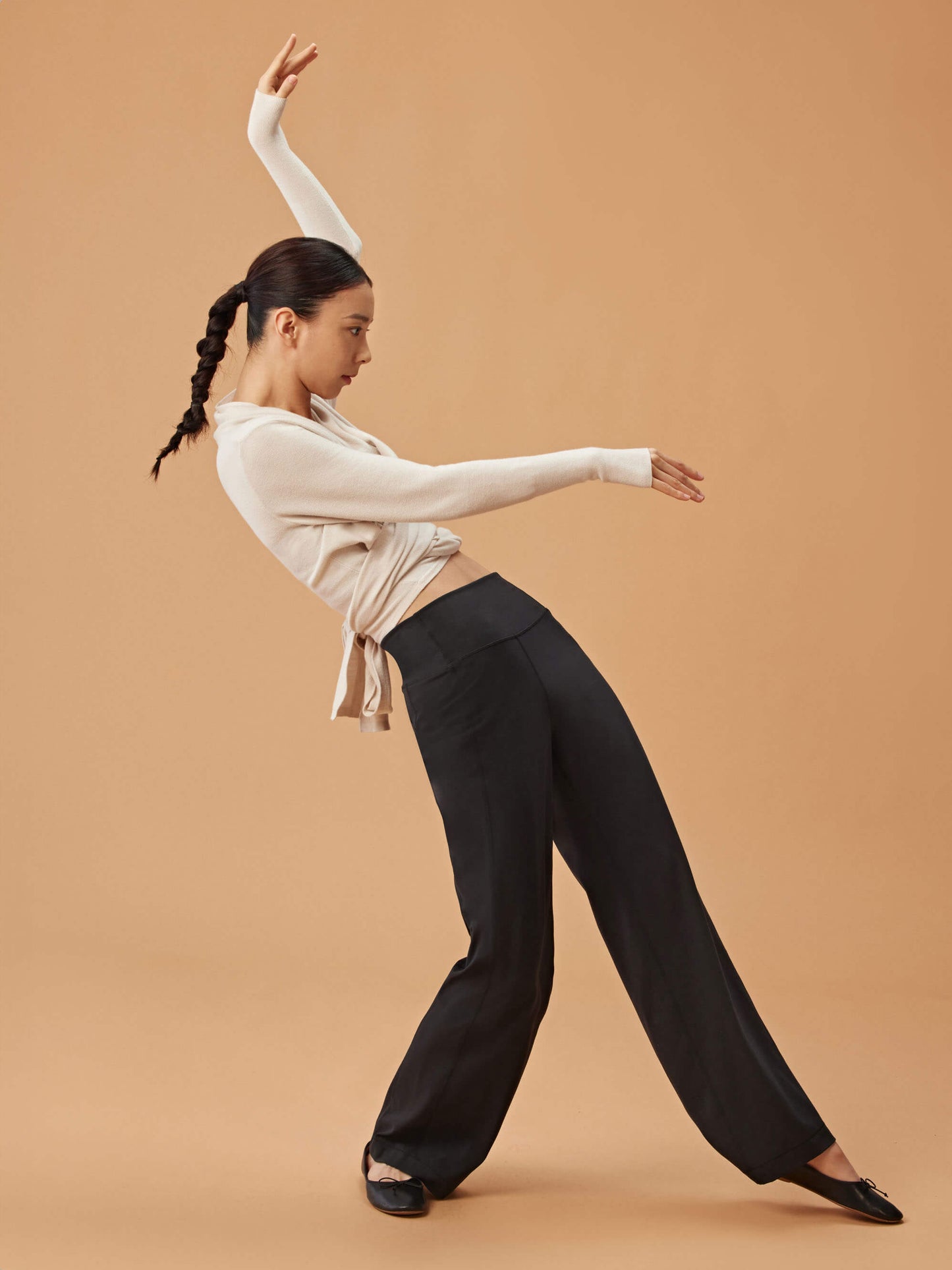 woman dancing in white cardigan, dark purple sports bra and black wide leg pants