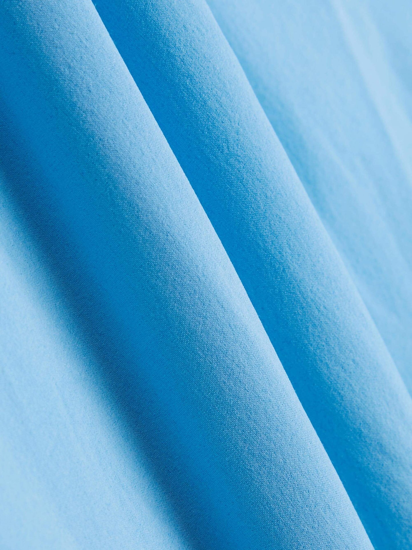 A close-up view of the light blue fabric of the training skort, showcasing its texture and smooth finish.