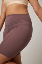 Woman wearing purple biker shorts and beige bra