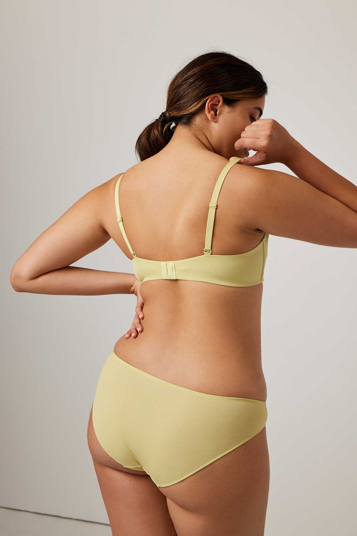 back of woman in lemon color bra and brief