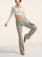 Model wearing a white long-sleeve top and beige pants on a plain background