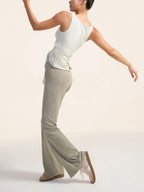 Model wearing a white top and gray flare pants