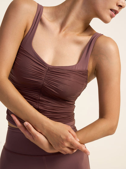 Model wearing a brown tank top with her arms crossed,