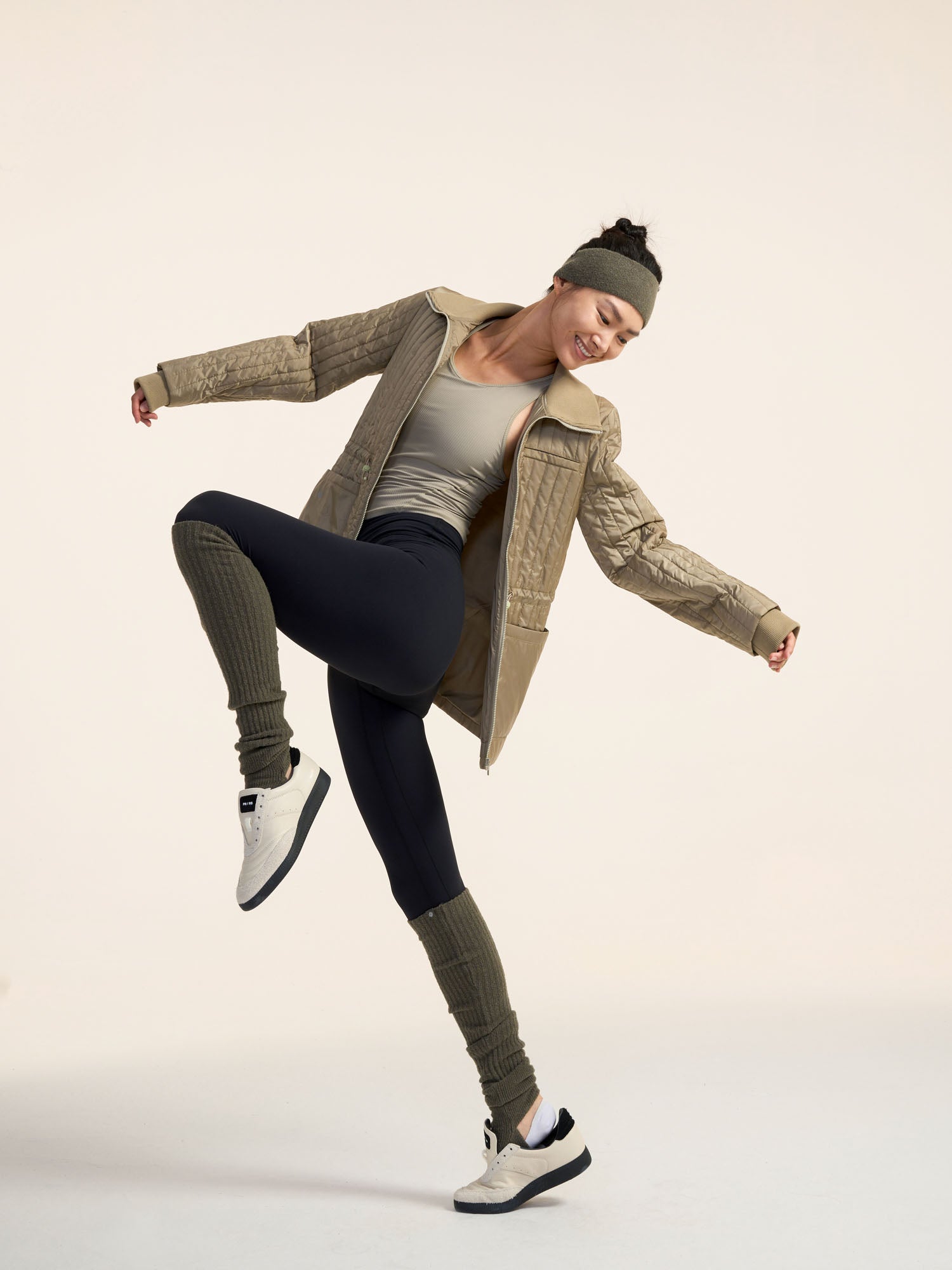 Model wearing green jacket, black leggings, and olive green leg warmers.