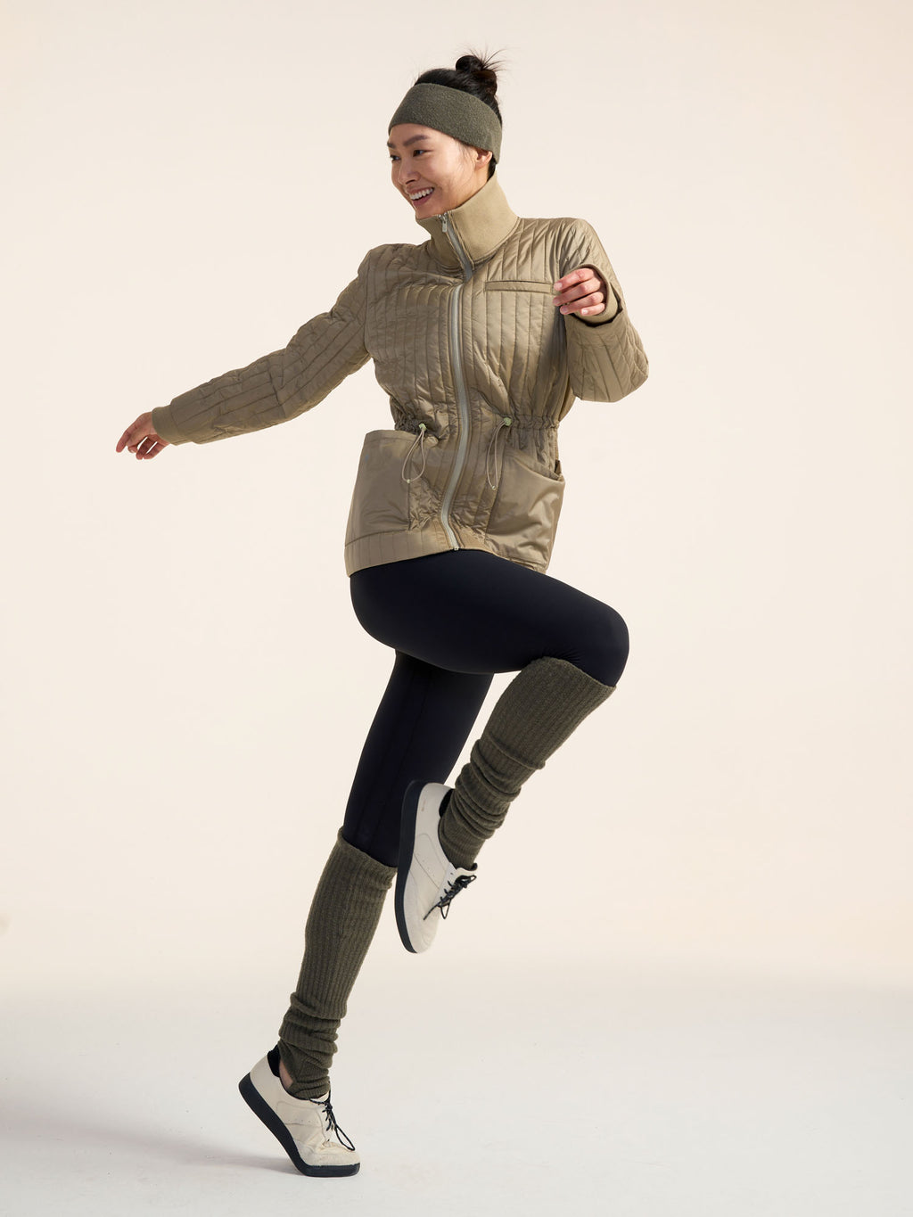 Model wearing green jacket, black leggings, and olive green leg warmers.