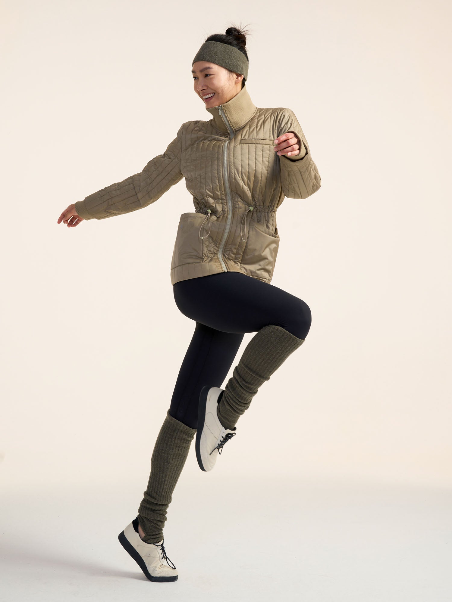 Model wearing green jacket, black leggings, and olive green leg warmers.
