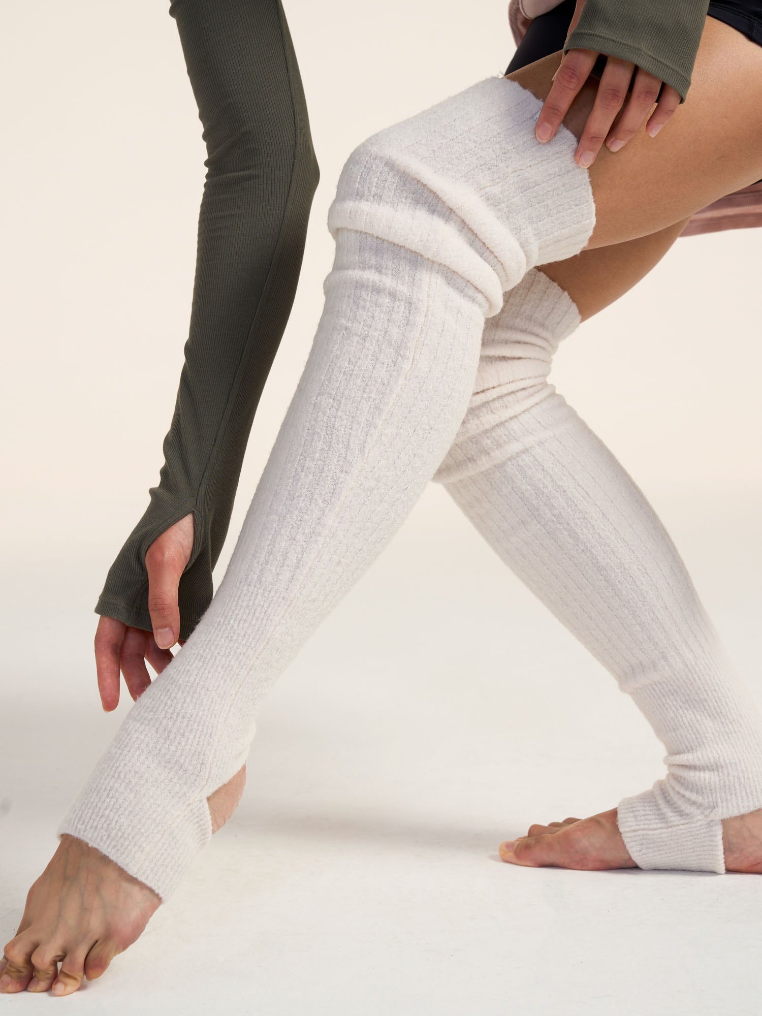 White knee-high leg warmer worn by a person on a plain background