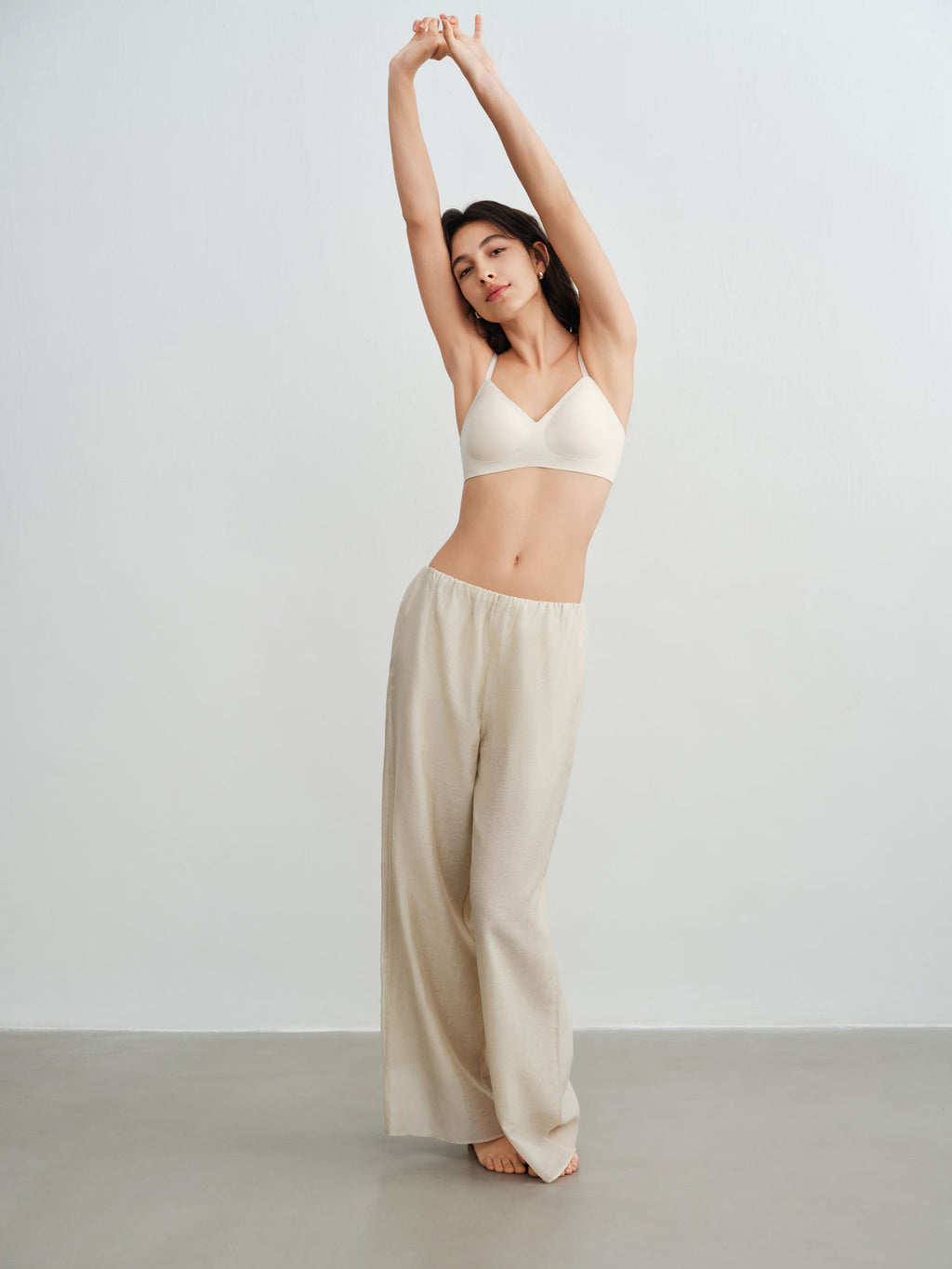 Model wearing a light cream colored bra and lounge pants. Sugar Swizzle color.