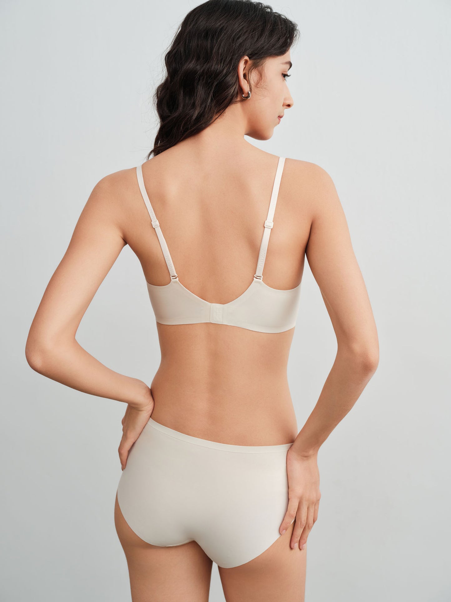 Back side of model wearing a light cream colored bra and brief set