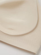 Fabric closeup of light cream bra padding on a white background. Sugar Swizzle color.