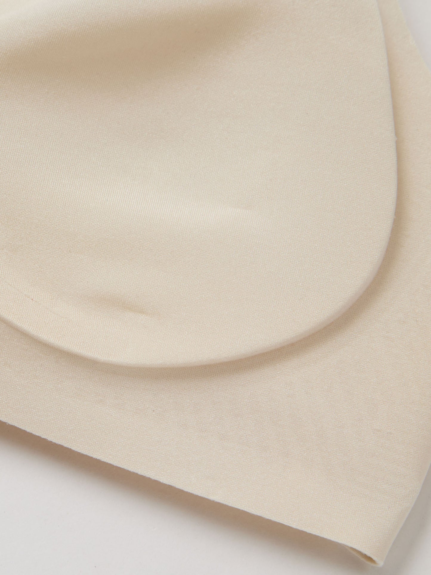 Fabric closeup of light cream bra padding on a white background