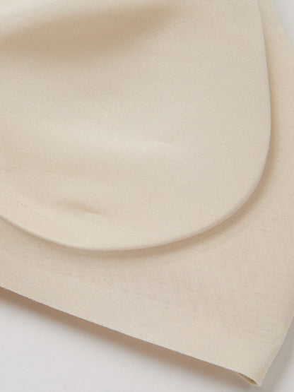 Fabric closeup of light cream bra padding on a white background