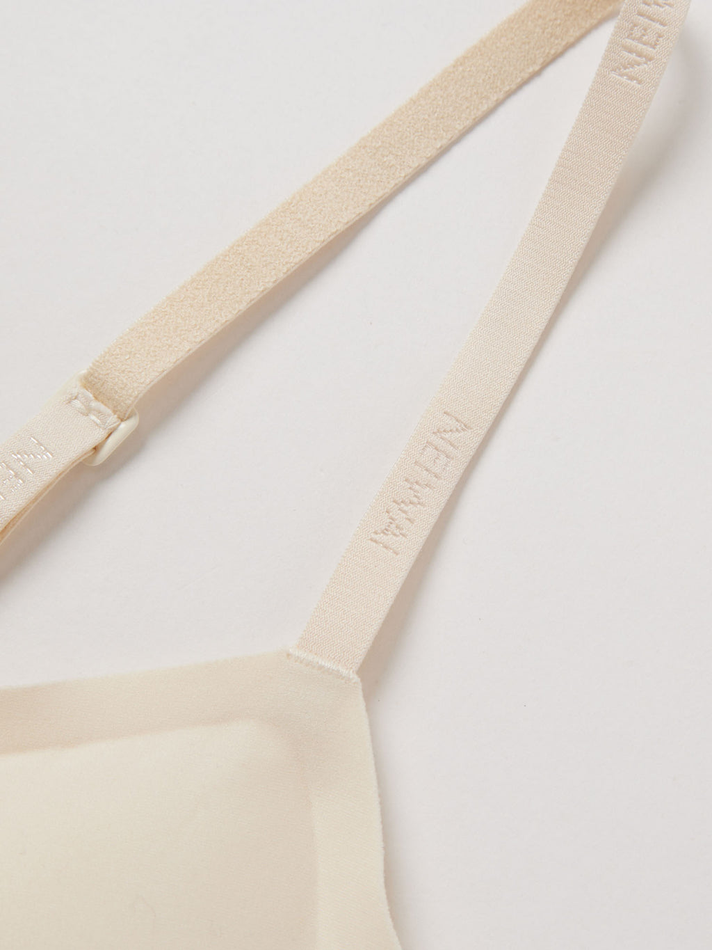 Close up of thin bra strap with NEIWAI logo. Sugar Swizzle color.