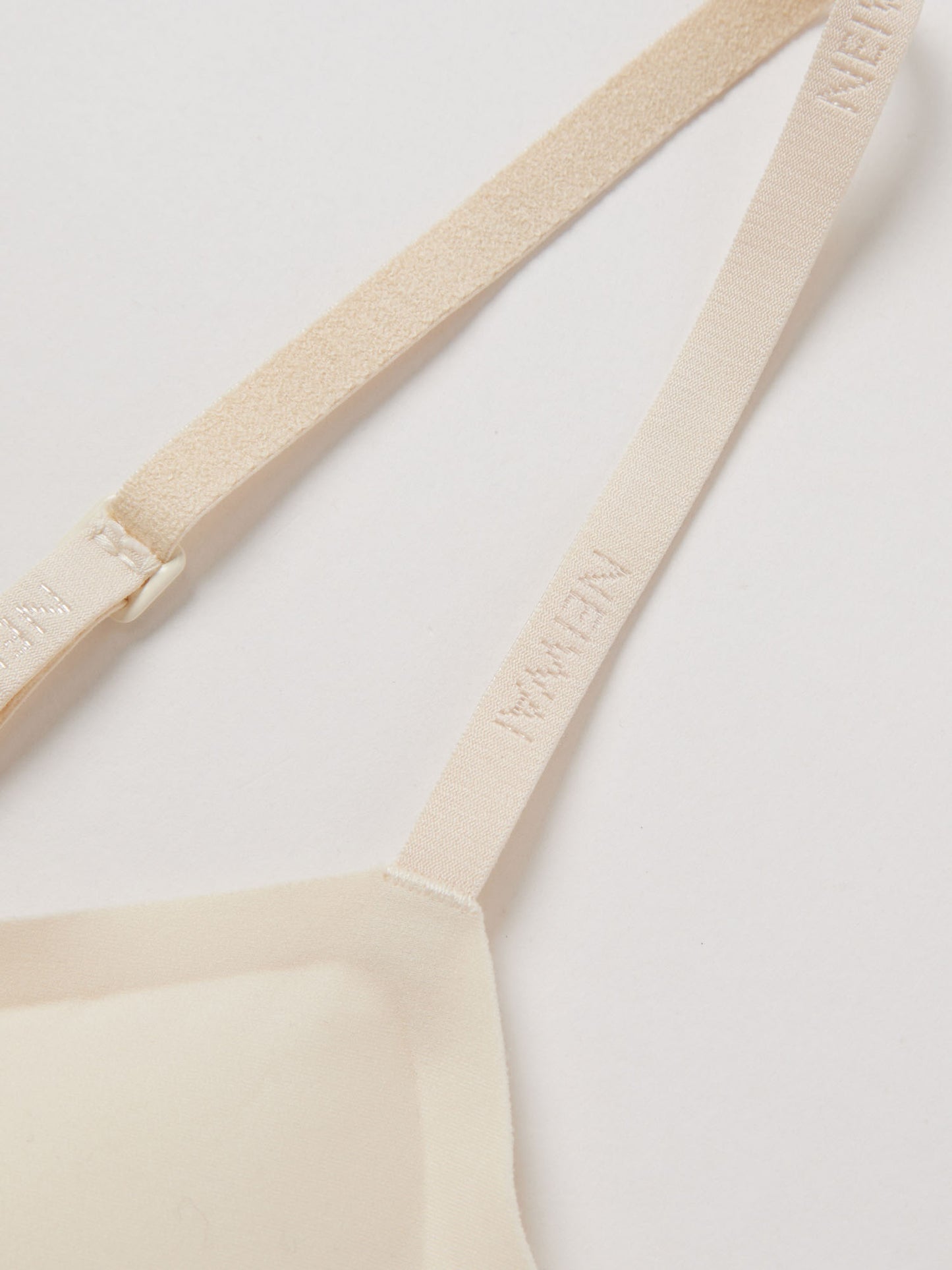 Close up of thin bra strap with NEIWAI logo