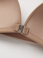 Close-up of a beige bra with a metal clasp on a white background.