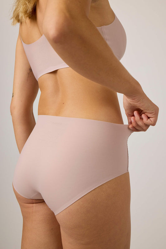 back of woman wearing light pink bra and brief