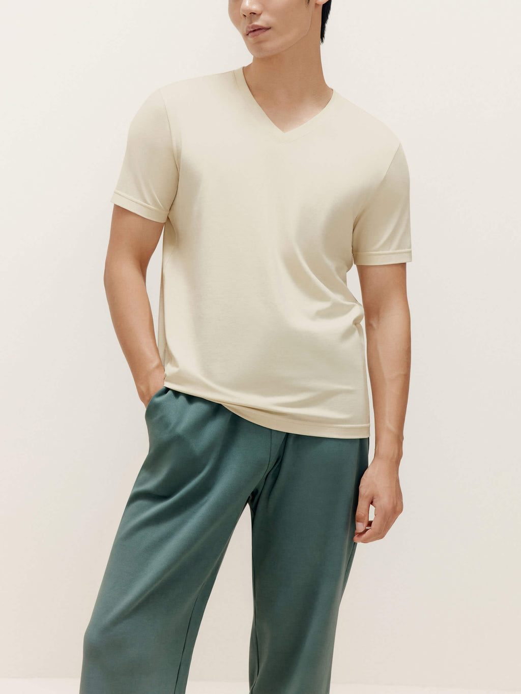 Man wearing beige V-neck T-shirt and teal lounge pants. Almond color.