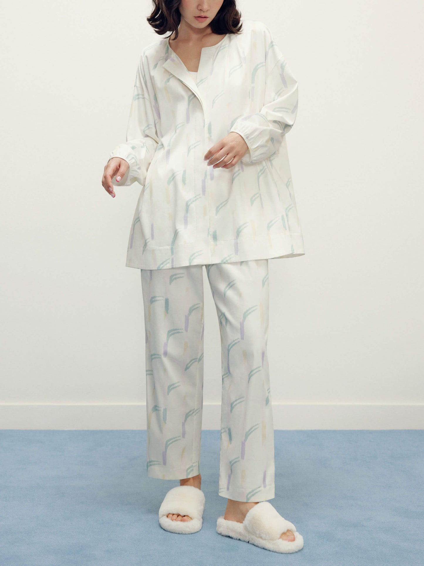 a woman wearing a white pajama sets with pattern and white slippers