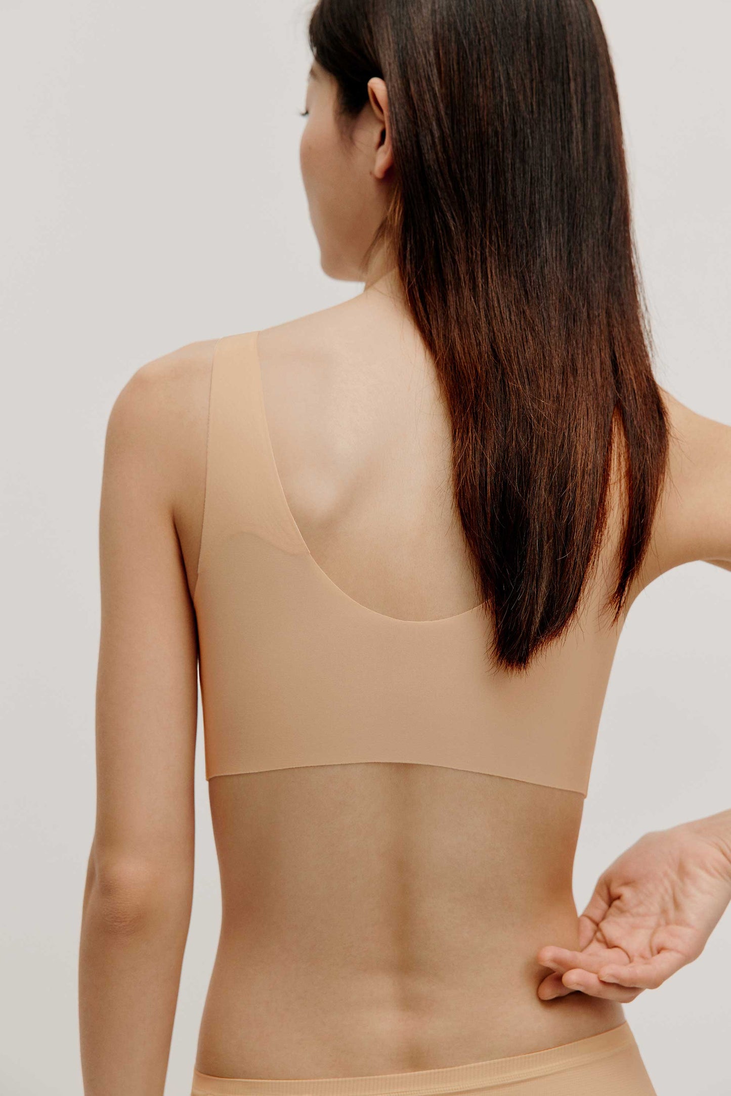 back of woman in beige bra and brief