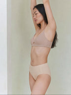 Model wearing a beige bra and briefs set against a plain background. Peach Pure color.