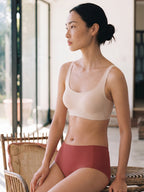 Woman wearing a beige sports bra and red high-waisted shorts sitting on a chair.