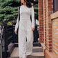 Woman wearing white sweatshirt and sweatpants with black bag over shoulders walking down stairs