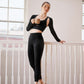 Dancer standing en pointe wearing long black sports bra, leggings, and shrug, holding a mug