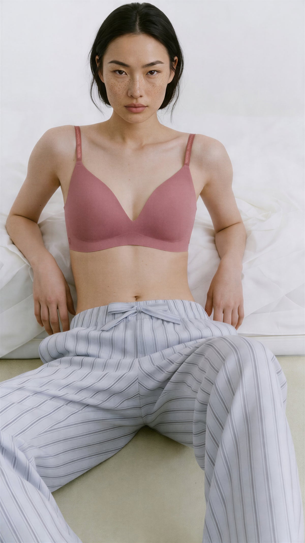 Woman wearing a pink bralette and striped pants on a white background,Taro Pink
