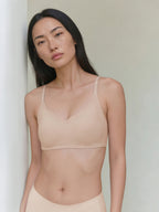 Model wearing a beige bra against a plain background. Treacly Almond color.