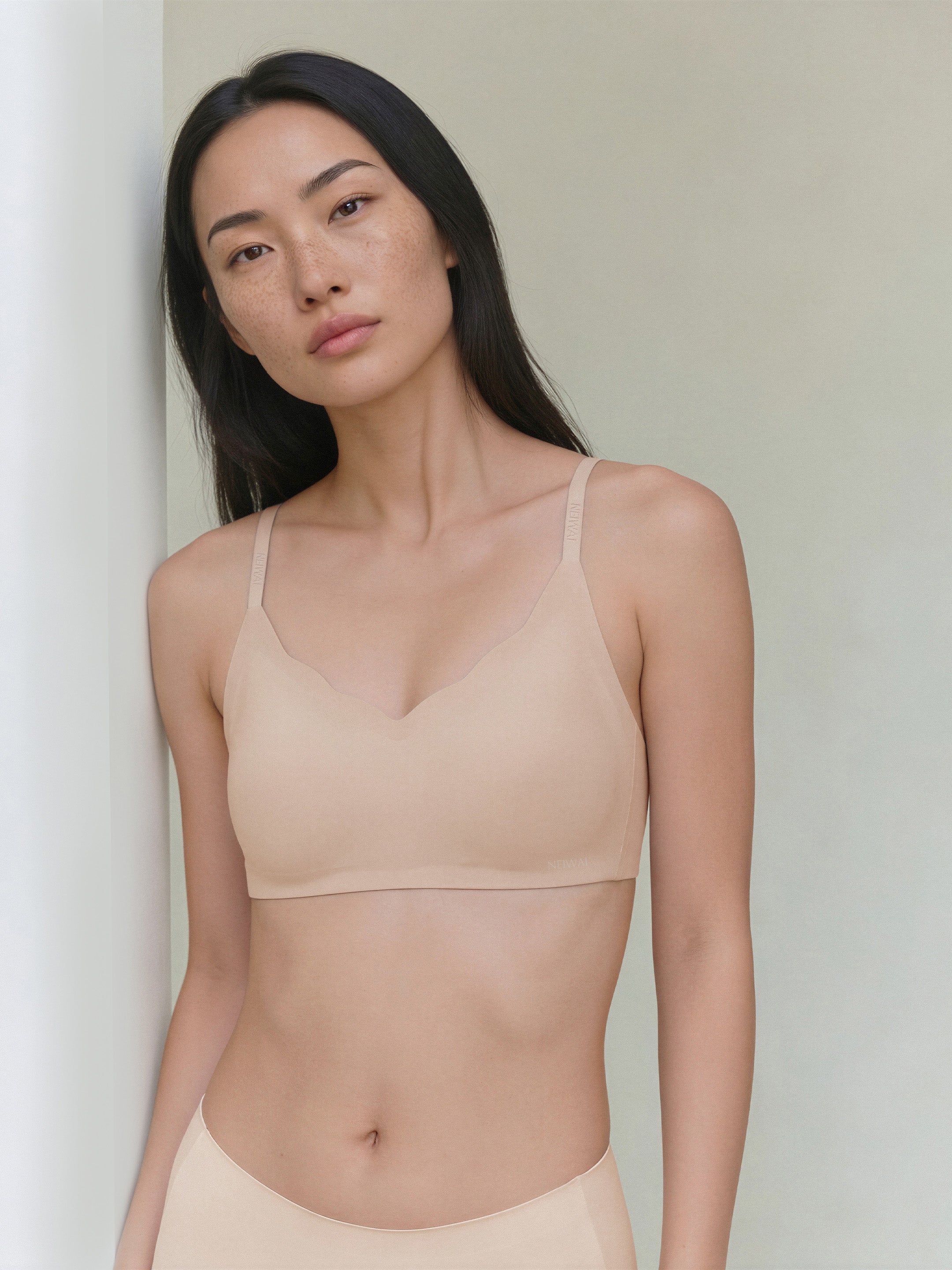 Model wearing a beige bra against a plain background