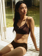 Woman wearing a brown bra sitting by a window with a garden view. Dark Brown color. 