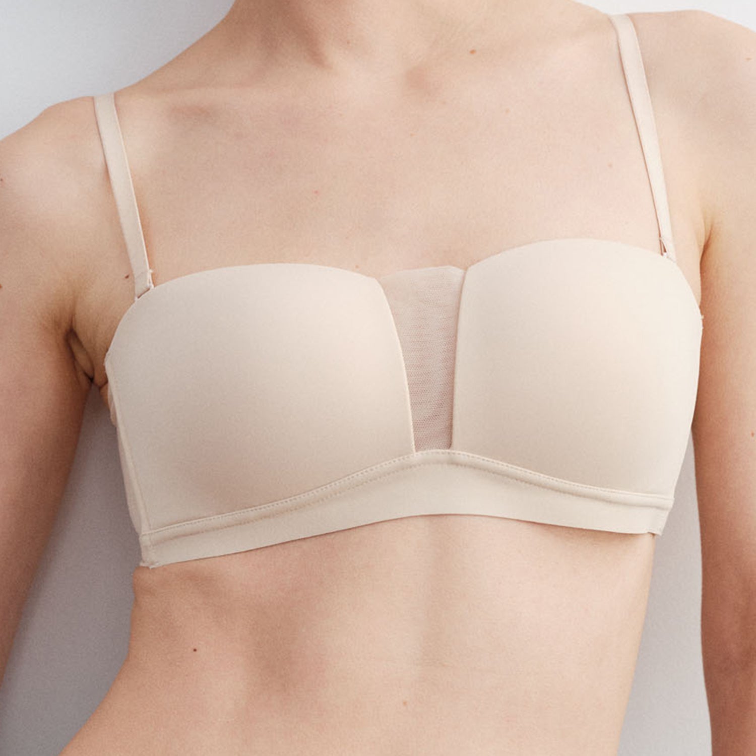 Beige bra worn by a person on a plain background
