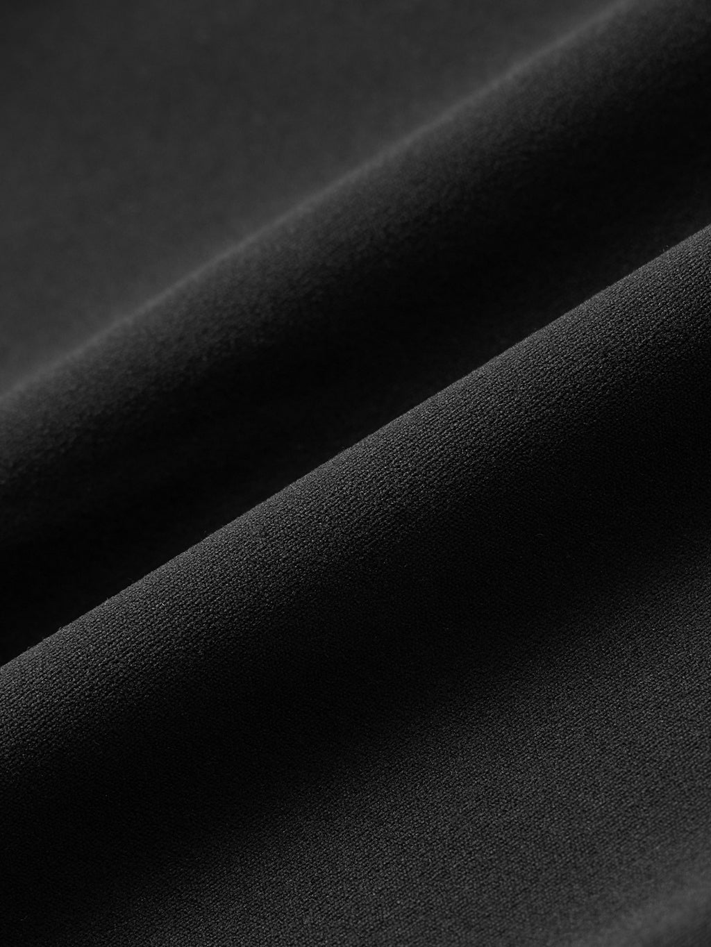 A close-up of draped black fabric with soft diagonal folds showing the material texture.
