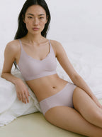 Woman wearing a light purple bra and panties set on a white background. Lotus root color. 