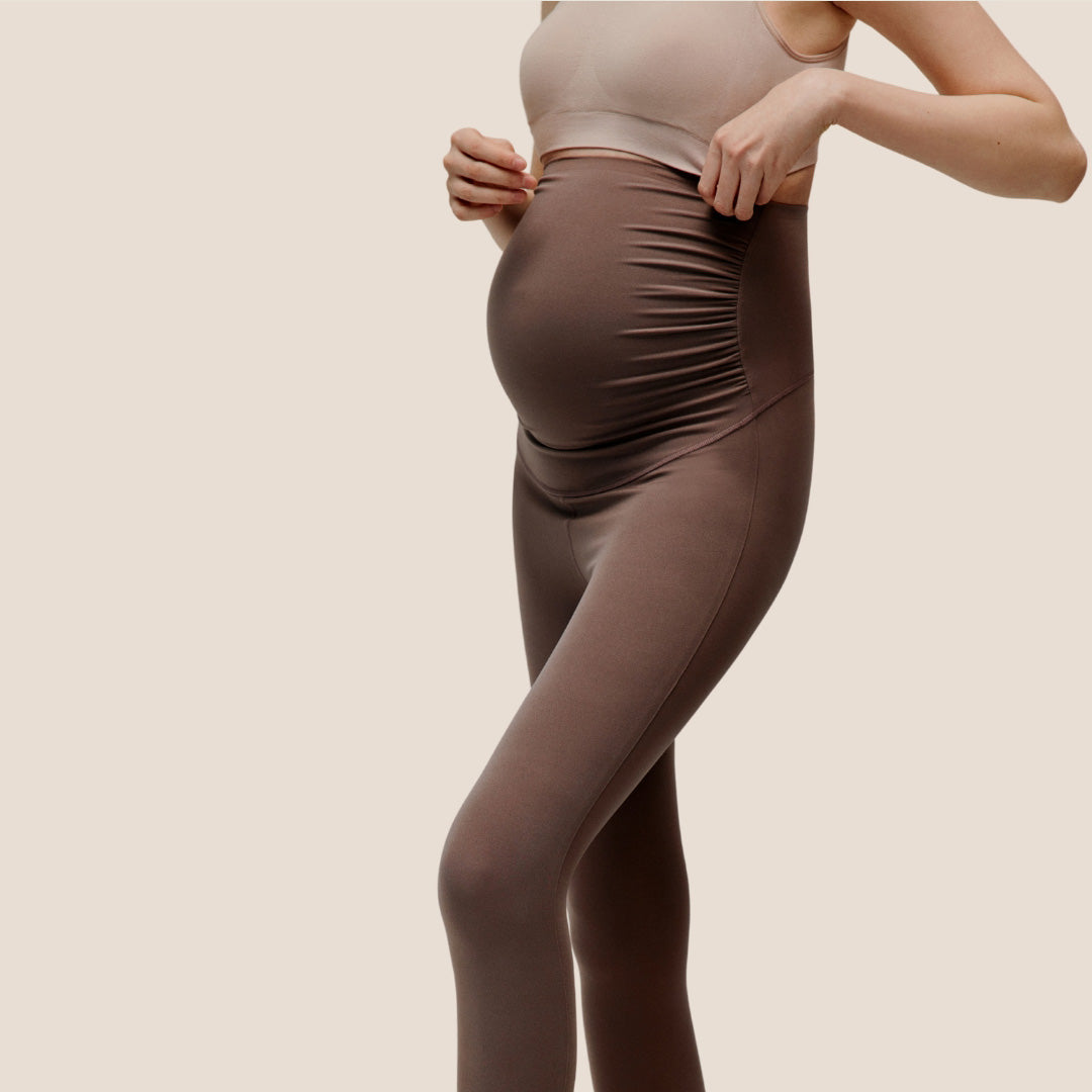 pregnant woman wearing a pair of brown maternity leggings