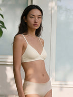 Woman wearing a beige bra and panties set outdoors.