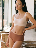Woman wearing a beige bikini top and brown bikini bottom in an outdoor setting.