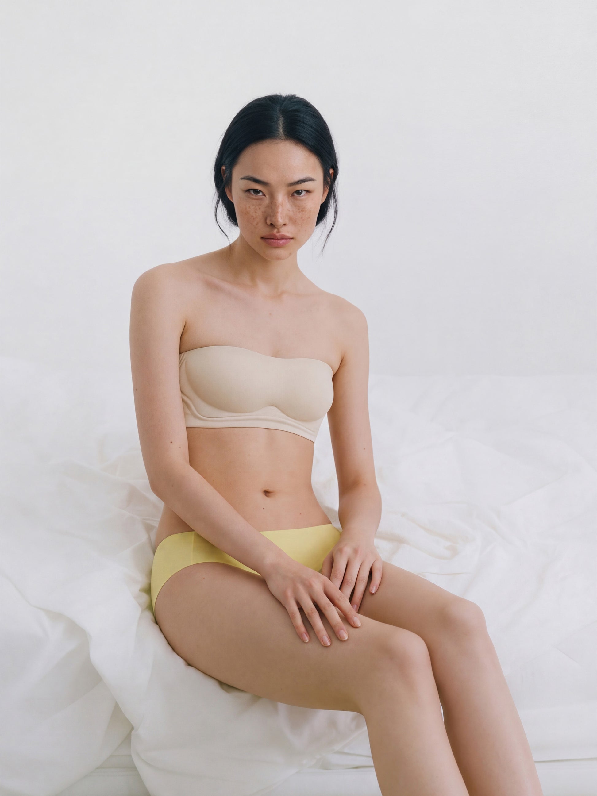 Woman wearing a beige strapless top and yellow underwear on a white background