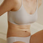 One woman sitting and wearing offwhite spaghetti strap bra and midwaist seamless brief.