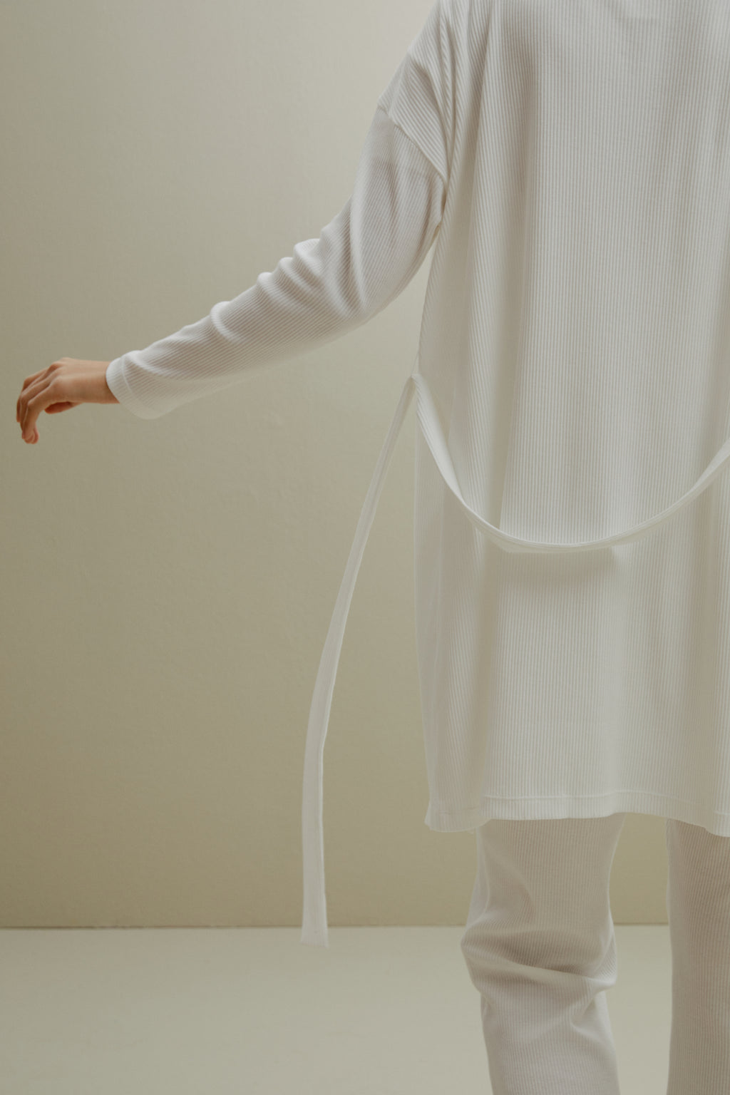 back of women in white ribbed cardigan and pants
