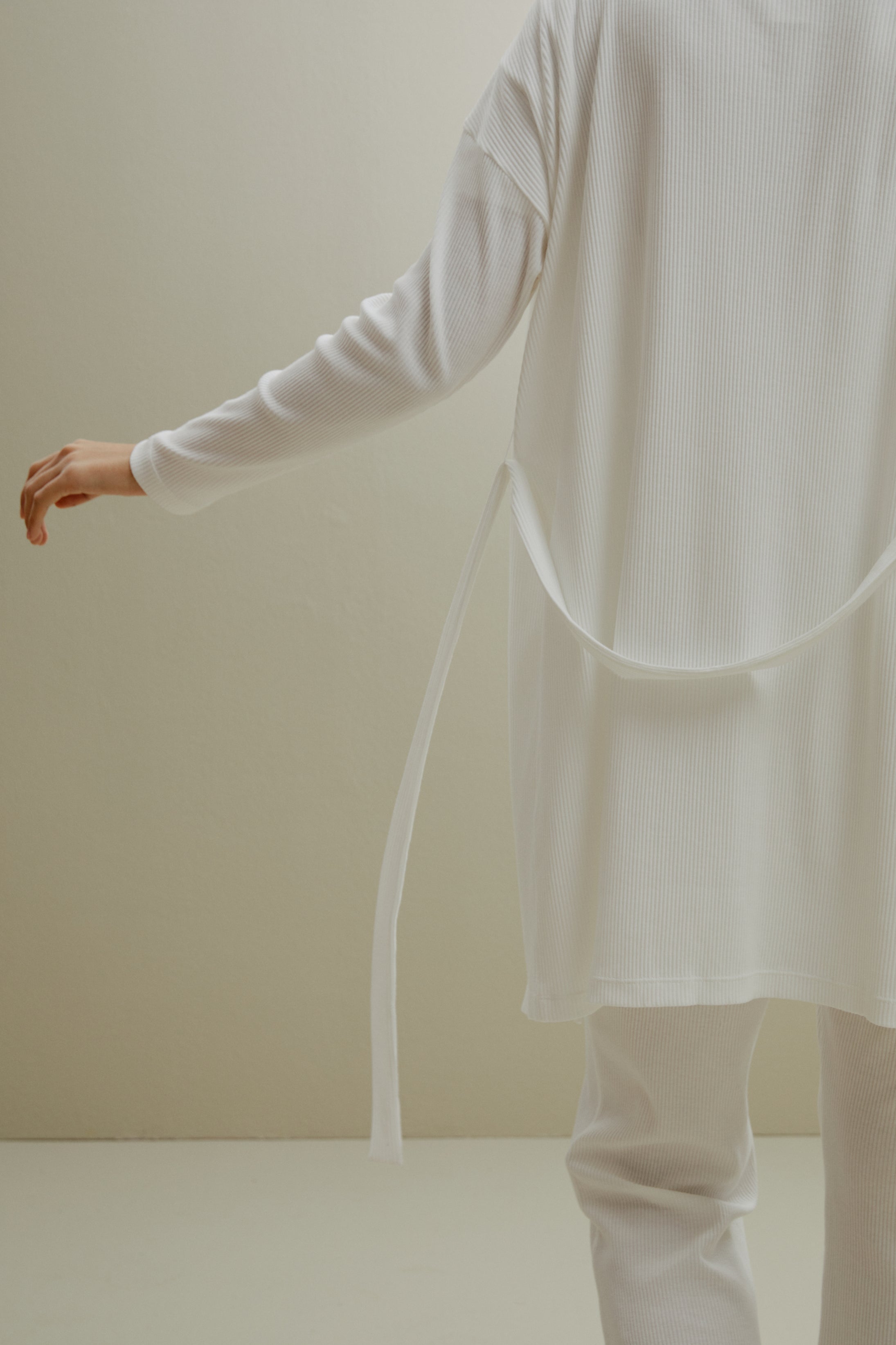 back of women in white ribbed cardigan and pants